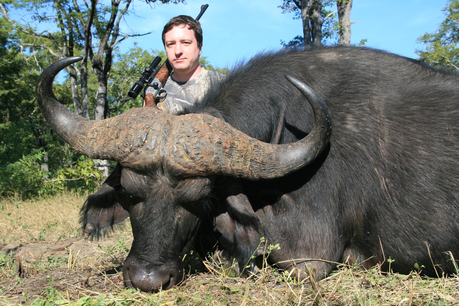 銃を持つハンターとアフリカスイギュウの記念写真
